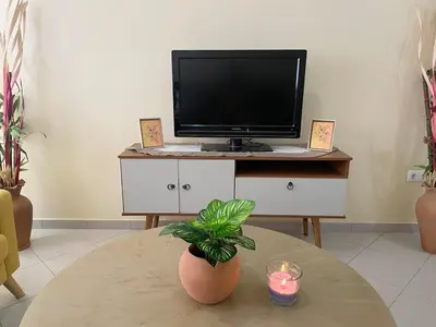 a living room with a tv and a table with a candle at Lovely comfortable apartment in Praia in Praia