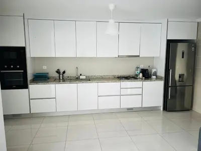 a kitchen with white cabinets and a stainless steel refrigerator at Apt T2 -Laginha -On The Beach in Mindelo
