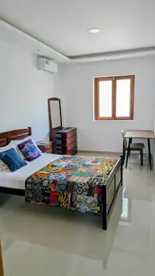 a bedroom with a bed in a room with a table at Nos Kaza in Cidade Velha