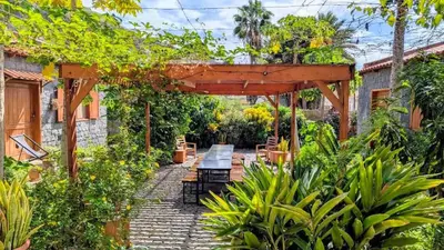 a garden with a wooden pergola and a table and benches at Nos Kaza in Cidade Velha