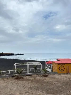 a building on the beach with the ocean in the background at Caetana e Ferro in Calheta