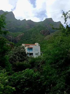 a house on a hill with mountains in the background at ROMANA guest house in Tarrafal da Vila de Ribeira Grande