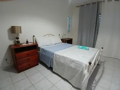a bedroom with a bed and a wooden dresser and a bed sidx sidx sidx at ROMANA guest house in Tarrafal da Vila de Ribeira Grande