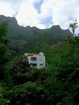 a house on a hill with mountains in the background at ROMANA guest house in Tarrafal da Vila de Ribeira Grande