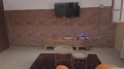 a living room with two tables and a tv on a brick wall at AnaSpace in Praia