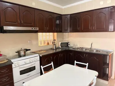 a kitchen with wooden cabinets and a white table in it at Casa Fernandes in Praia