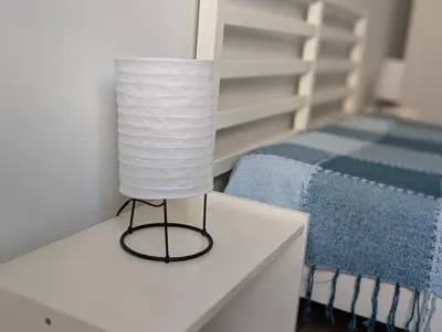 a lamp on a white table next to a bed at Apartamento Espargos in Espargos