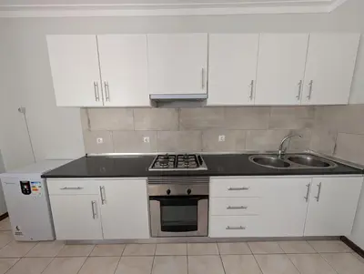 a kitchen with white cabinets and a stove and a sink at Apartamento Espargos in Espargos