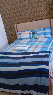 a bed with a blue and white striped blanket and pillows at Topklass homes in Praia