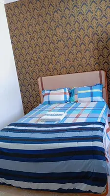 a bed with a blue striped comforter and two pillows at Topklass homes in Praia