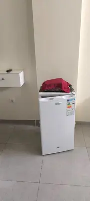 a small white refrigerator with a red bag on top at Pires's House in Mindelo