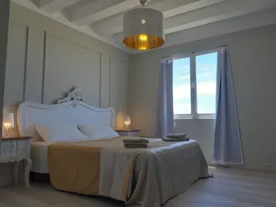 a white bedroom with a large bed and a window at Ca' Zen in Sal Rei