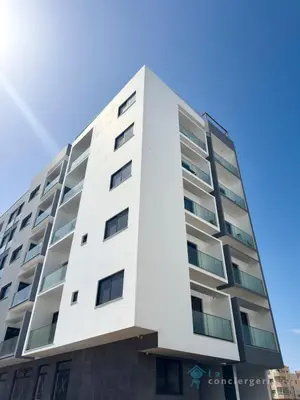 a tall white building with a blue sky in the background at 2 bdr aprt, stunning view, rooftop pool - LCGR in Praia