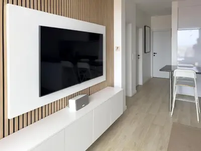 a living room with a large television on a wall at 2 bdr aprt, stunning view, rooftop pool - LCGR in Praia
