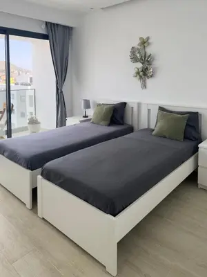 two beds in a white bedroom with blue sheets at Spacious 2 bdr aprt, rooftop pool - LCGR in Praia