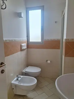 a bathroom with a toilet and a sink and a window at Apart T2 em frente à Praia - Centro de Santa Maria in Santa Maria