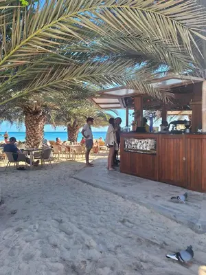 a group of people standing at a bar on the beach at Apart T2 em frente à Praia - Centro de Santa Maria in Santa Maria