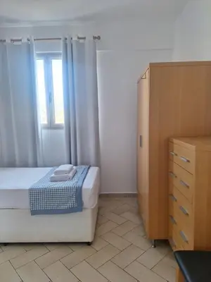 a bedroom with a bed and a dresser and a window at Apart T2 em frente à Praia - Centro de Santa Maria in Santa Maria