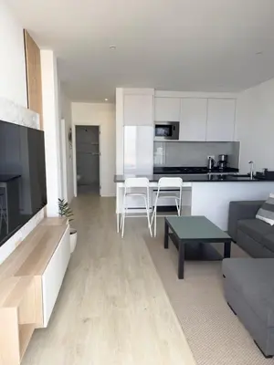 a living room and kitchen with a couch and a table at Cozy 2 bdr aprt, rooftop pool - LCGR in Praia