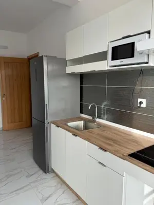 a kitchen with white cabinets and a stainless steel refrigerator at AQUÁRIO Hotel in Sal Rei