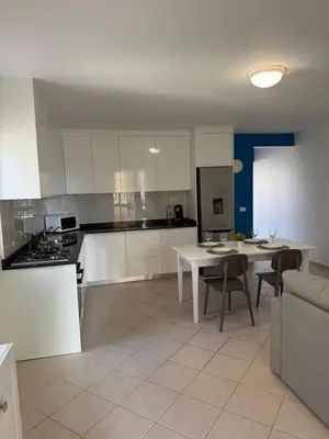 a kitchen with white cabinets and a table and chairs at Estrela do Sul Santa Maria by RPG Group in Santa Maria