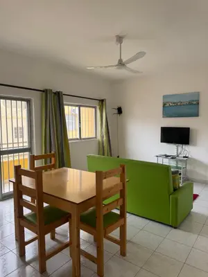 a living room with a table and a green couch at Legacy cv in Praia