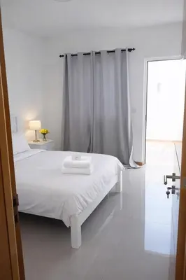 a white bedroom with a white bed and a window at Ti Jona Rooms in Mindelo