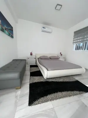 a white bedroom with a bed and a rug at Coraçon di Mindel Apartment in Mindelo