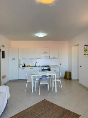 a kitchen with white cabinets and a table and chairs at Apartament POR DO SOL A9 praia Cabral wi-fi free Sal Rei in Sal Rei