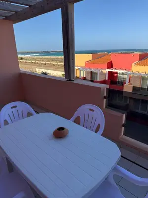 a white table and chairs in a room with a view of the beach at Apartament POR DO SOL A9 praia Cabral wi-fi free Sal Rei in Sal Rei
