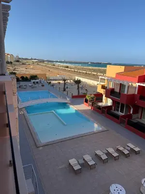 a view of a swimming pool with chairs and the beach at Apartament POR DO SOL A9 praia Cabral wi-fi free Sal Rei in Sal Rei
