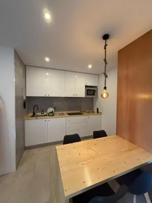 a kitchen with a wooden table and white cabinets at HostySpot - Bloco Verde in Santa Maria