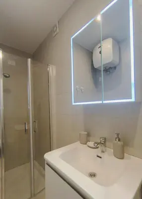a bathroom with a sink and a shower with a mirror at HostySpot - Bloco Verde in Santa Maria