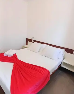 a bedroom with a bed with a red blanket on it at Pousada do Norte, ilha do Fogo in Calheta de São Miguel