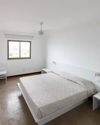 a white bedroom with a bed and two tables at Pousada do Norte, ilha do Fogo in Calheta de São Miguel