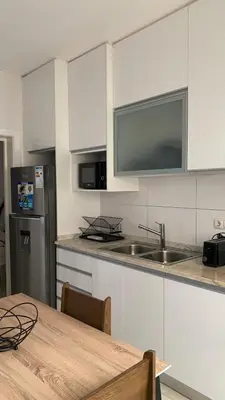a kitchen with white cabinets and a wooden table at Apartamento T3 palmarejo center in Praia