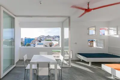 a white room with a table and a bed and a window at Modern Flat in Mindelo - 3B in Mindelo