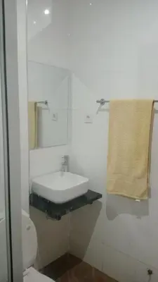 a white bathroom with a sink and a mirror at Praia Sunset Horizon Apartment