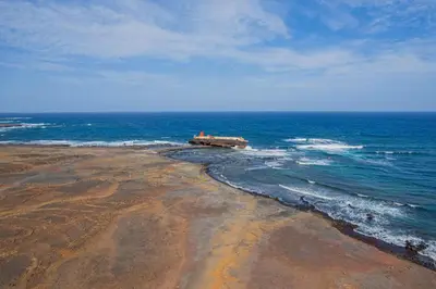 a beach with a building in the middle of the ocean at Hospedaria Santo António in Praia Baixo