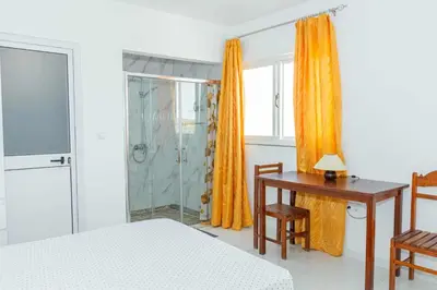 a bedroom with a bed and a desk and a shower at Hospedaria Santo António