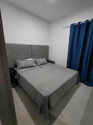a bedroom with a large bed with a blue curtain at C&C Guesthouse in Praia