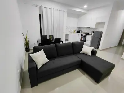 a living room with a black couch and a kitchen at C&C Guesthouse in Praia