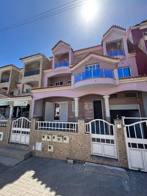 a large brick house with blue windows and white gates at La casa de iman in Praia