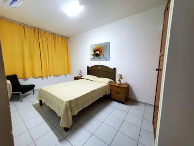 a bedroom with a bed and a chair and yellow curtains at Comfort T2 in Espargos
