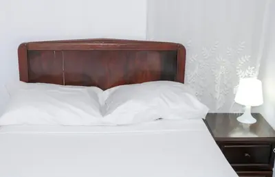 a bed with a wooden headboard and a table with a lamp at Quinta Toca do leão in Ribeira Grande