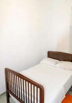 a bed with a wooden frame and white sheets at Quinta Toca do leão in Ribeira Grande
