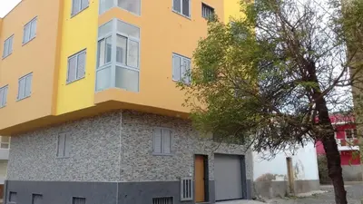 a yellow and gray building with a tree at Private Apartament Celestina & Carlos in Mindelo