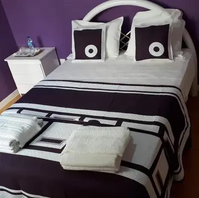 a large bed with black and white sheets and pillows at Chez Zuzu in Mindelo