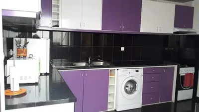 a kitchen with purple cabinets and a washing machine at Chez Zuzu in Mindelo