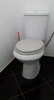 a white toilet in a bathroom with a red brush at Chez Zuzu in Mindelo